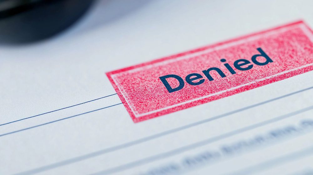 A clear close-up of a stamped Denied notice on an insurance form, showing the struggle of navigating insurance limitations